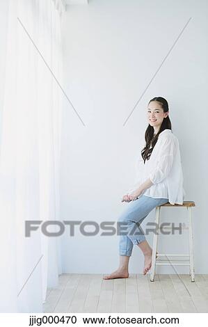 Young woman sitting with book in the living room View Large Photo Image Stock Image - Young woman sitting with book in the living room. Fotosearch