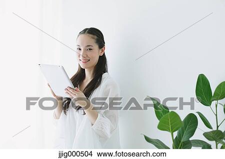 Young woman sitting with tablet in the living room View Large Photo Image Picture - Young woman sitting with tablet in the living room. Fotosearch