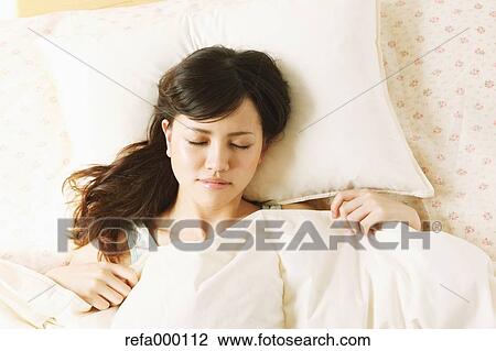 Stock Image - Young woman sleeping in bed. Fotosearch