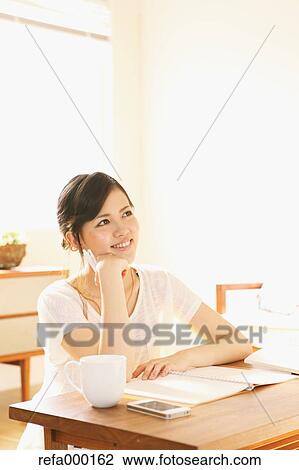 Stock Image - Young woman studying in the living room. Fotosearch