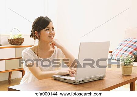 Young woman using PC in the living room View Large Photo Image Picture - Young woman using PC in the living room. Fotosearch