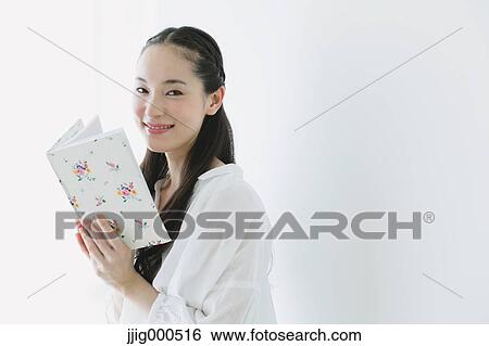 Stock Photograph - Young woman with book in the living room. Fotosearch