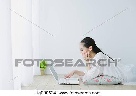 Young woman with laptop in the living room View Large Photo Image Picture - Young woman with laptop in the living room. Fotosearch