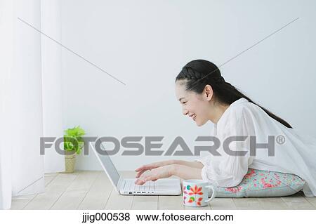 Stock Photo - Young woman with laptop in the living room. Fotosearch