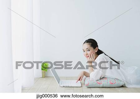 Young woman with laptop in the living room View Large Photo Image Stock Photograph - Young woman with laptop in the living room. Fotosearch