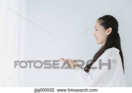 Stock Image - Young woman with long hair raising arms. Fotosearch
