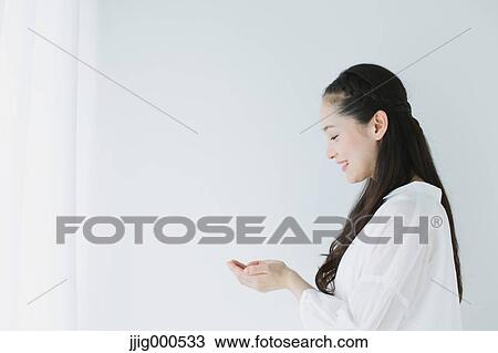 Stock Image - Young woman with long hair raising arms. Fotosearch
