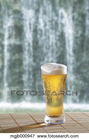 Stock Photo - Glass of beer and waterfall. Fotosearch