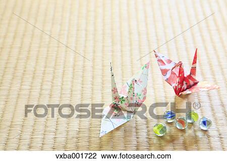 Stock Image - Origami cranes and marbles on tatami mat. Fotosearch