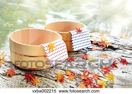 Stock Photography - Maple leaves and wooden buckets at Japanese traditional hot spring. Fotosearch