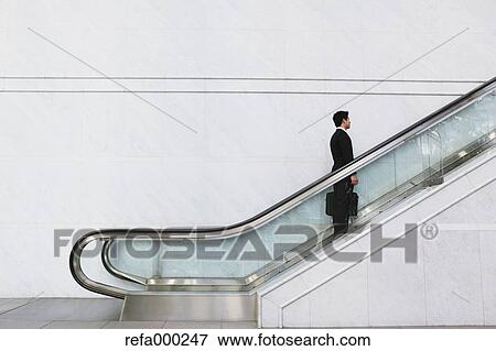Businessman on escalator View Large Photo Image Stock Photo - Businessman on escalator. Fotosearch