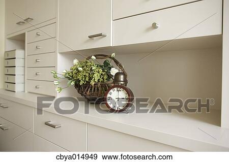 Stock Photo - Flowers and clock on white shelf. Fotosearch