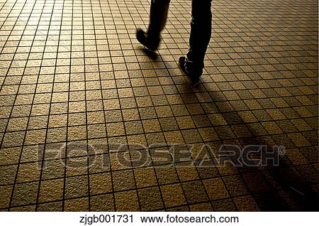 Stock Image - Man walking on tiled sidewalk. Fotosearch