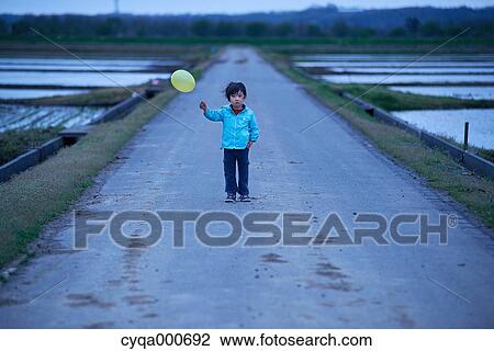 Stock Image - Japanese kid with balloon in the countryside. Fotosearch