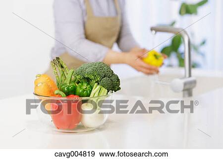 Woman washing vegetables in the kitchen View Large Photo Image Stock Photo - Woman washing vegetables in the kitchen. Fotosearch