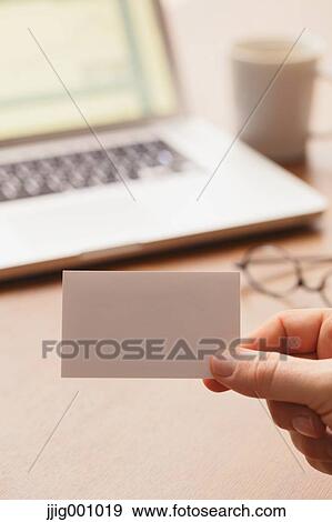 Close up of male hand holding business card with laptop in the background View Large Photo Image Stock Photo - Close up of male hand holding business card with laptop in the background. Fotosearch