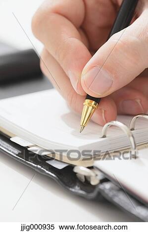 Stock Photography - Close up of male hand writing on agenda. Fotosearch