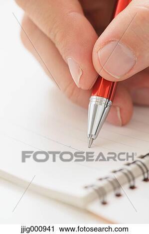Stock Image - Close up of male hand writing on notebook. Fotosearch