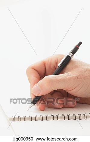 Stock Image - Close up of male hand writing on notebook. Fotosearch