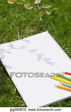 Stock Photography - Colored pencil and sketchbook on grass. Fotosearch