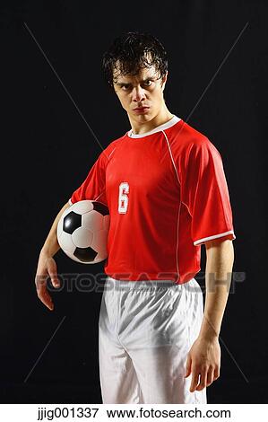 Football player in a white and red uniform standing against black background View Large Photo Image Stock Photo - Football player in a white and red uniform standing against black background. Fotosearch