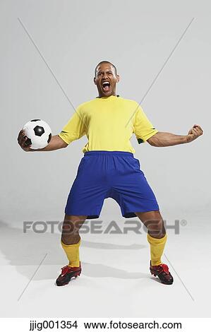 Football player in a yellow and blue uniform standing against white background View Large Photo Image Picture - Football player in a yellow and blue uniform standing against white background. Fotosearch