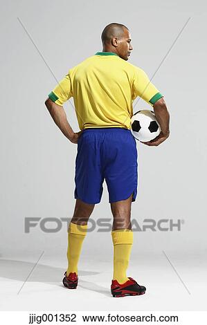 Football player in a yellow and blue uniform standing against white background View Large Photo Image Stock Image - Football player in a yellow and blue uniform standing against white background. Fotosearch