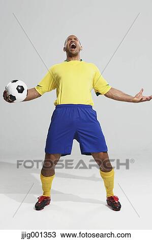 Stock Image - Football player in a yellow and blue uniform standing against white background. Fotosearch