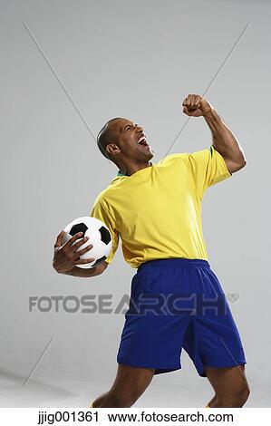 Football player in a yellow and blue uniform standing against white background View Large Photo Image Stock Image - Football player in a yellow and blue uniform standing against white background. Fotosearch