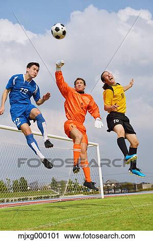 Stock Image - Football players aiming for the ball. Fotosearch