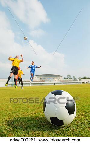 Stock Image - Football players aiming for the ball. Fotosearch