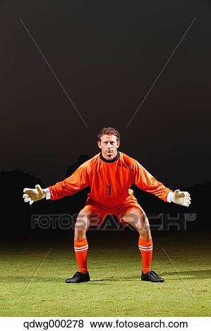 Goalkeeper in orange uniform standing in soccer field View Large Photo Image Stock Photo - Goalkeeper in orange uniform standing in soccer field. Fotosearch