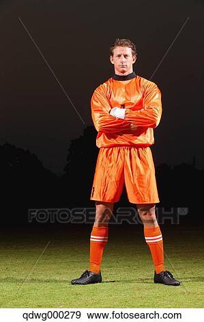 Goalkeeper in orange uniform standing in soccer field View Large Photo Image Stock Photo - Goalkeeper in orange uniform standing in soccer field. Fotosearch