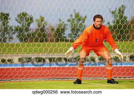Goalkeeper in orange uniform standing in soccer field View Large Photo Image Stock Photograph - Goalkeeper in orange uniform standing in soccer field. Fotosearch