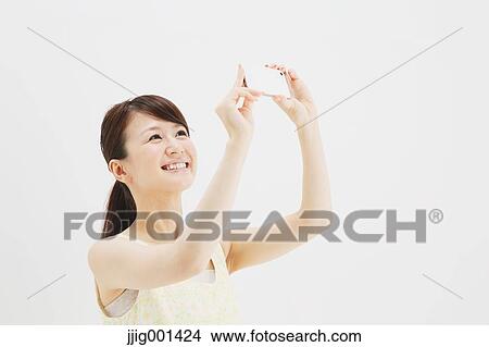 Japanese young woman in a one piece dress with smartphone against white background View Large Photo Image Picture - Japanese young woman in a one piece dress with smartphone against white background. Fotosearch