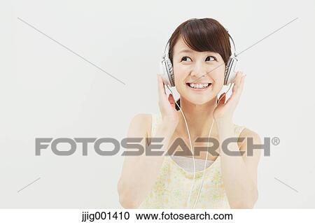 Japanese young woman in a one piece dress with earphones standing against white background View Large Photo Image Stock Image - Japanese young woman in a one piece dress with earphones standing against white background. Fotosearch