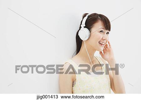 Japanese young woman in a one piece dress with earphones standing against white background View Large Photo Image Stock Image - Japanese young woman in a one piece dress with earphones standing against white background. Fotosearch