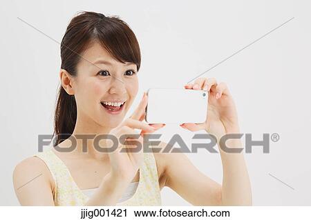 Stock Image - Japanese young woman in a one piece dress with smartphone against white background. Fotosearch