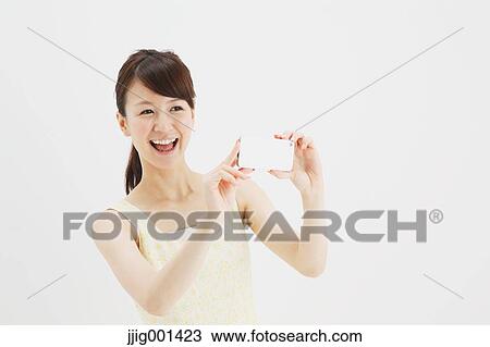 Stock Image - Japanese young woman in a one piece dress with smartphone against white background. Fotosearch