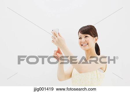 Stock Photo - Japanese young woman in a one piece dress with smartphone against white background. Fotosearch