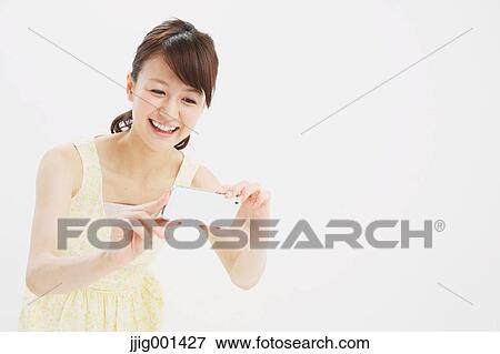 Stock Photo - Japanese young woman in a one piece dress with smartphone against white background. Fotosearch