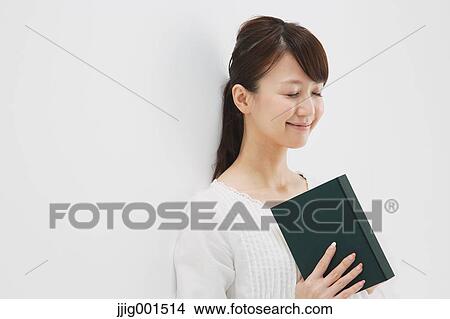 Japanese young woman in a white shirt with a book against white background View Large Photo Image Picture - Japanese young woman in a white shirt with a book against white background. Fotosearch