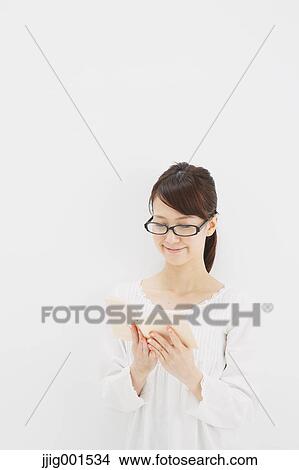 Japanese young woman in a white shirt with a book against white background View Large Photo Image Picture - Japanese young woman in a white shirt with a book against white background. Fotosearch