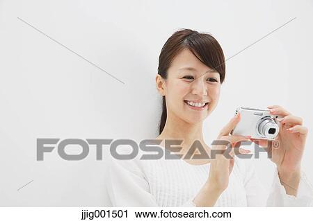 Japanese young woman in a white shirt with digital camera against white background View Large Photo Image Stock Image - Japanese young woman in a white shirt with digital camera against white background. Fotosearch