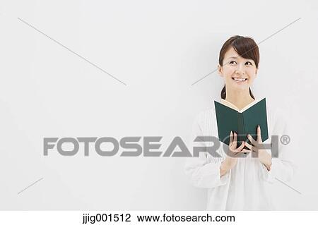Stock Image - Japanese young woman in a white shirt with a book against white background. Fotosearch