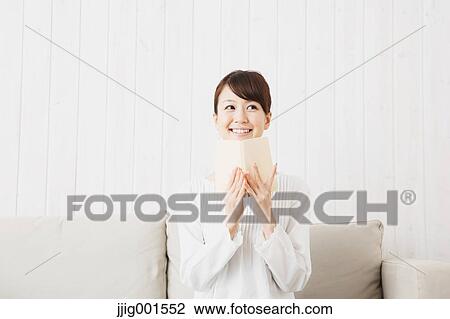 Japanese young woman in a white shirt with a book on the sofa View Large Photo Image Stock Image - Japanese young woman in a white shirt with a book on the sofa. Fotosearch