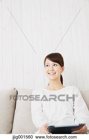 Japanese young woman in a white shirt with tablet on the sofa View Large Photo Image Stock Image - Japanese young woman in a white shirt with tablet on the sofa. Fotosearch