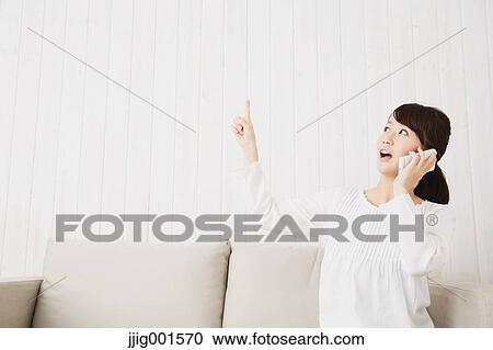 Japanese young woman in a white shirt with smartphone on the sofa View Large Photo Image Stock Image - Japanese young woman in a white shirt with smartphone on the sofa. Fotosearch