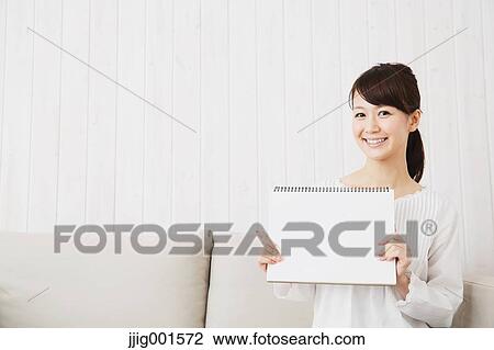 Japanese young woman in a white shirt with sketchbook on the sofa View Large Photo Image Stock Image - Japanese young woman in a white shirt with sketchbook on the sofa. Fotosearch