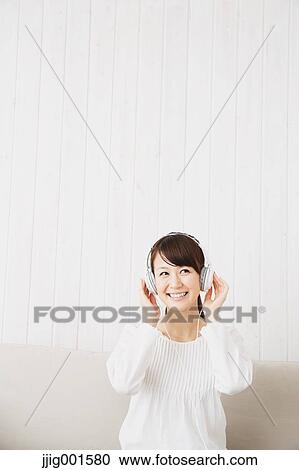 Japanese young woman in a white shirt with earphones on the sofa View Large Photo Image Stock Image - Japanese young woman in a white shirt with earphones on the sofa. Fotosearch